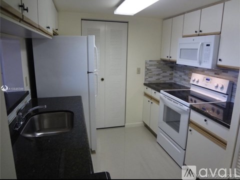 A kitchen with white cabinets and a black countertop.