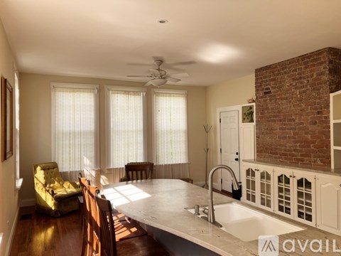 A living room with a yellow chair and a brick fireplace.