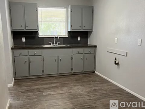 A kitchen with grey cabinets and a wooden floor.