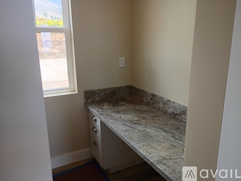 A kitchen counter with a window overlooking a driveway.