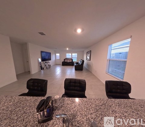 A spacious living room with black leather chairs and a granite countertop.