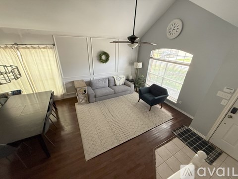 A living room with a grey couch and a wreath on the wall.