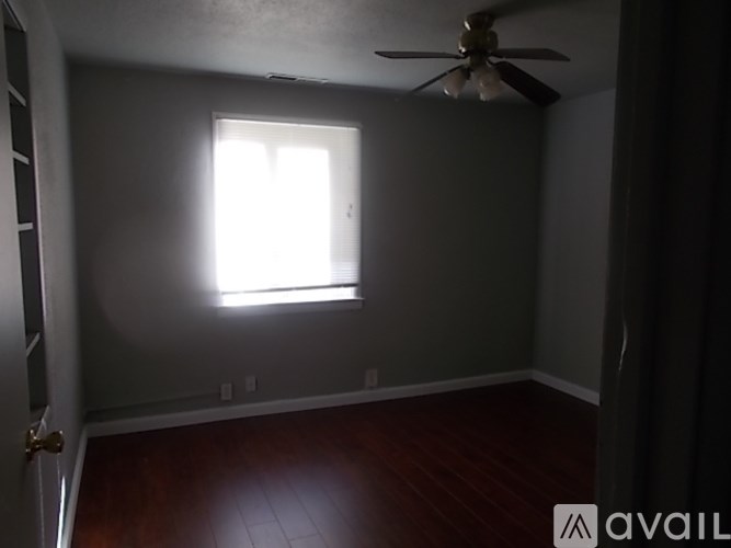 A room with a ceiling fan and a window letting in light.