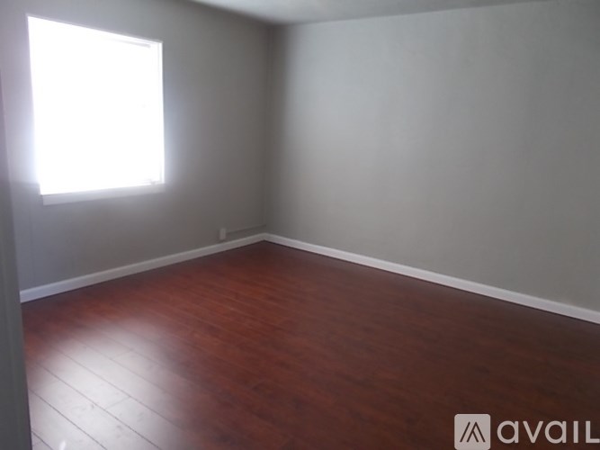 A room with wooden flooring and a window letting in light.