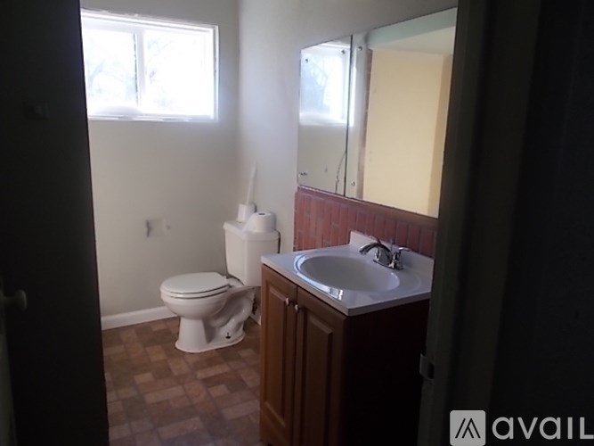 A bathroom with a toilet, sink, and mirror.