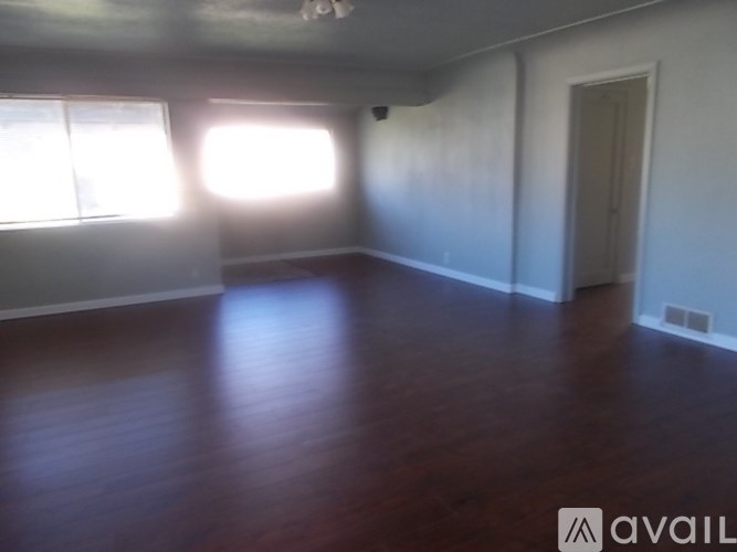 A room with wooden floors and two windows.