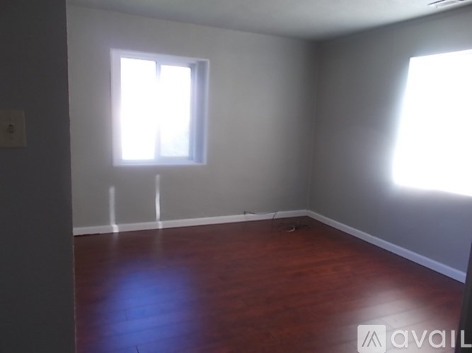 A room with wooden floors and two windows.