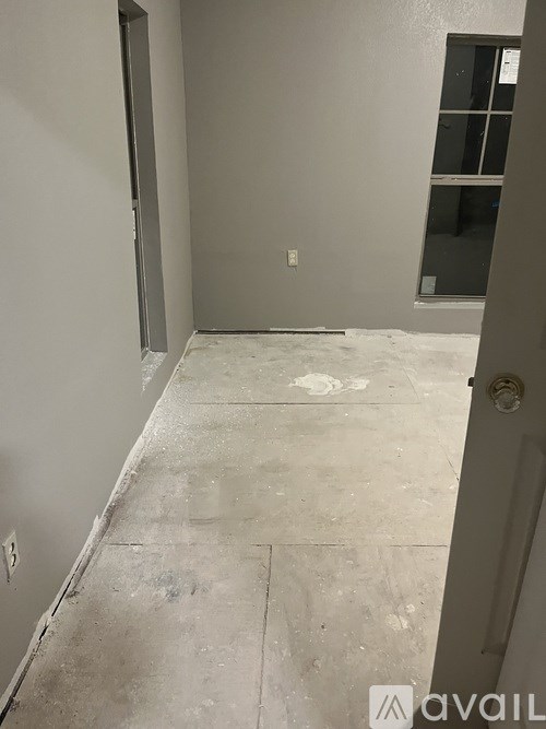 A room with a concrete floor and walls, and a door on the right side.