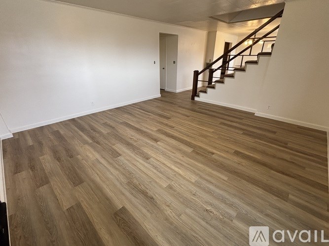 A room with wooden flooring and a staircase.