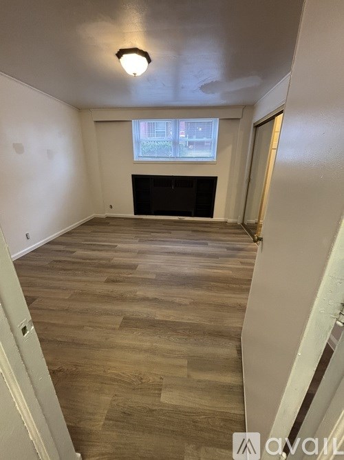 A room with wooden flooring and a window.