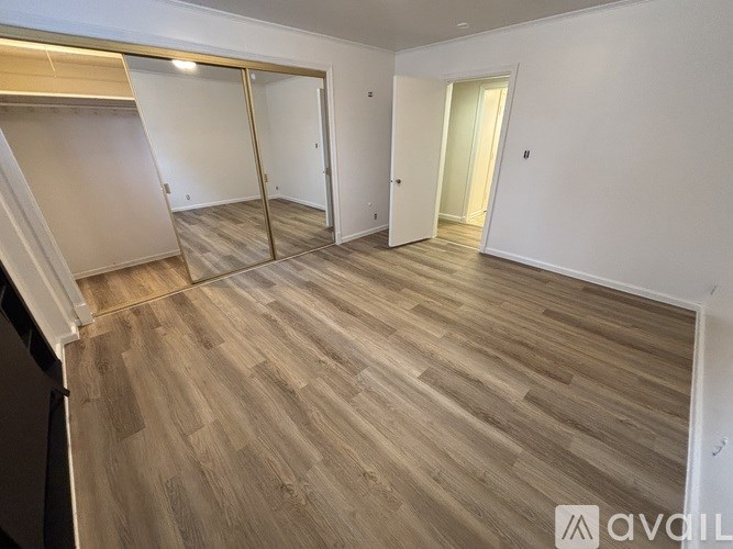 A room with wooden flooring and white walls, with a sliding door in the middle.