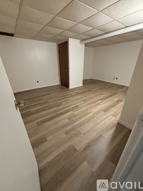 A room with wooden flooring and a door on the left side.