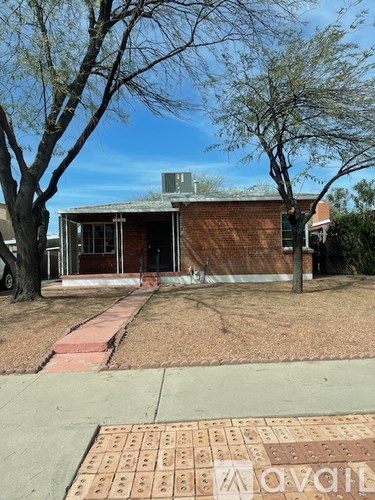 A house with a brick wall and a tree in front.