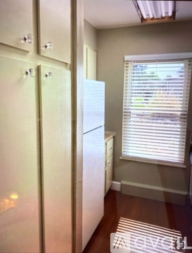 A white refrigerator in a kitchen with a window.