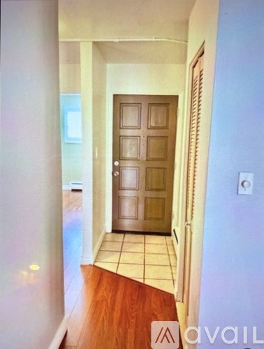 A hallway with a wooden door and tiled floor.