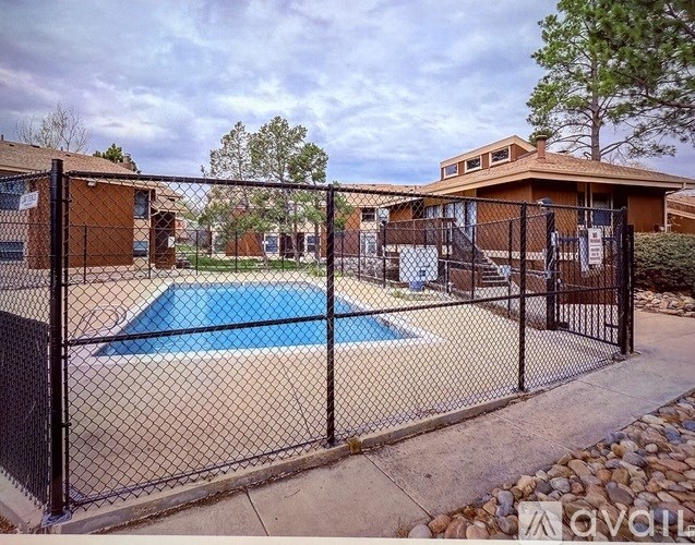 A black fence surrounds a blue swimming pool.