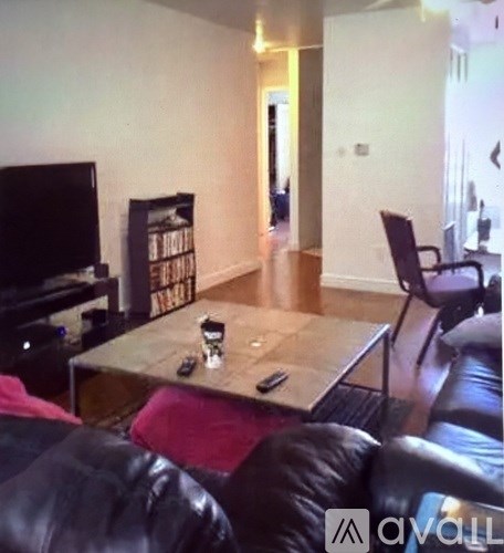A living room with a black leather couch and a wooden coffee table.