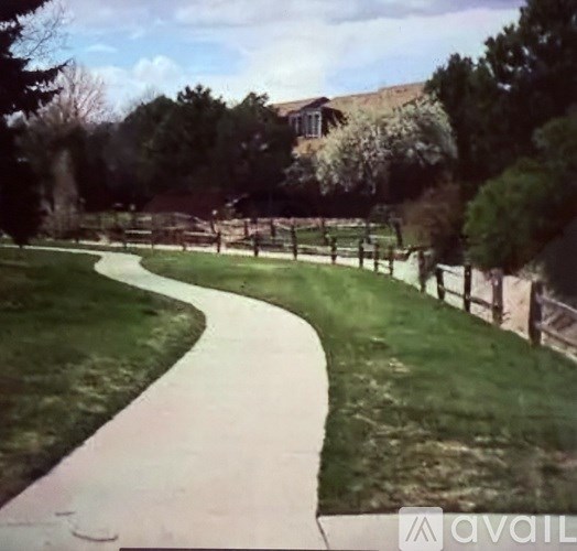 A pathway in a park with a wooden fence on the right side.