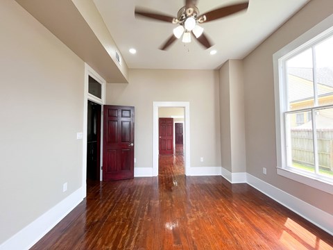 A room with a ceiling fan and wooden floors.