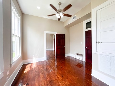 A room with a ceiling fan and wooden floors.