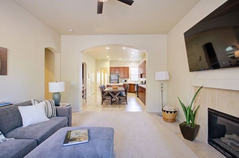 A living room with a grey couch and a fireplace.