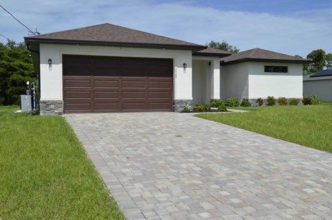 A house with a brown garage door and a brick driveway.