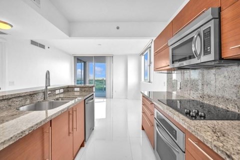 A modern kitchen with a sink, stove, and microwave.