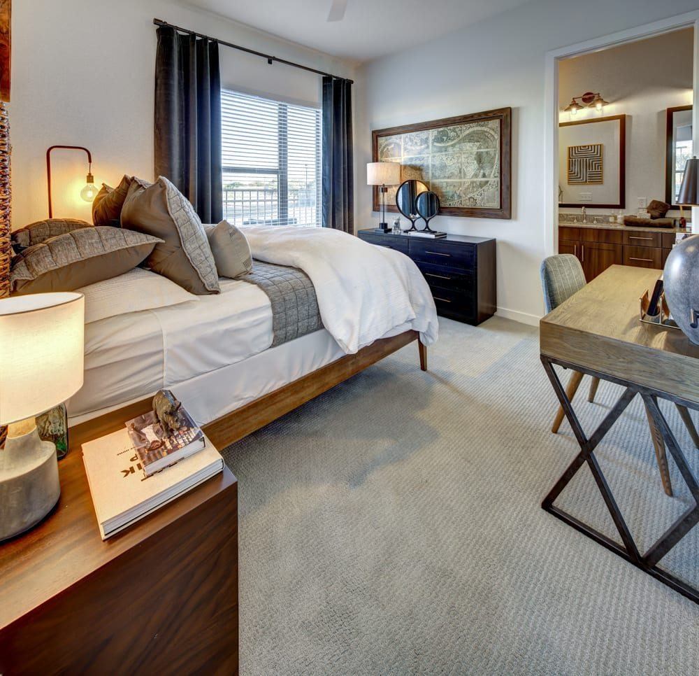 A bedroom with a large bed and a desk with a chair.