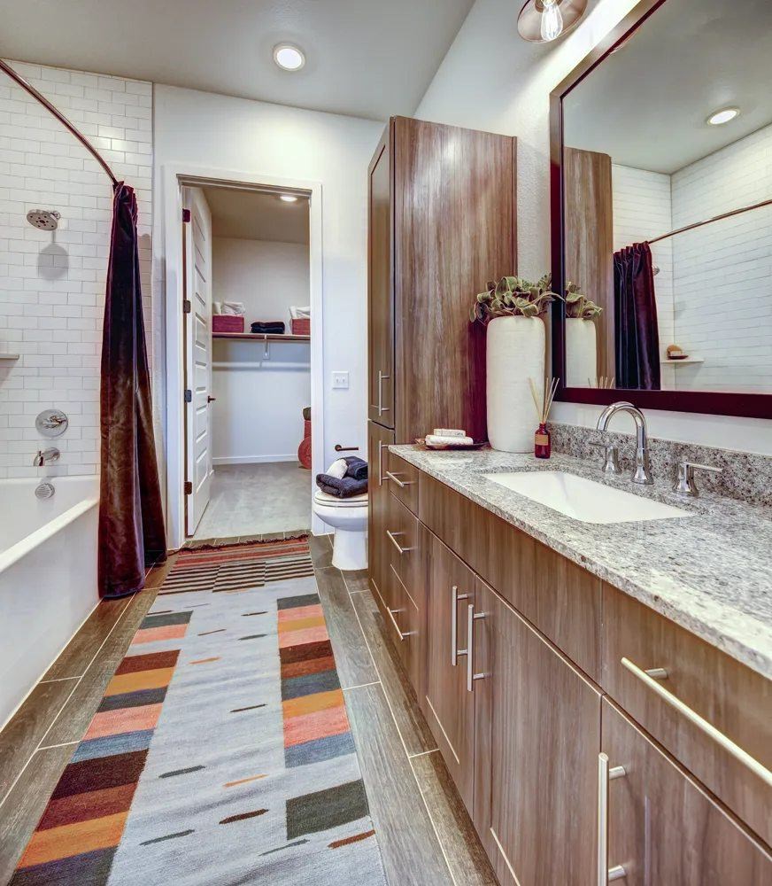 A bathroom with a striped rug on the floor.