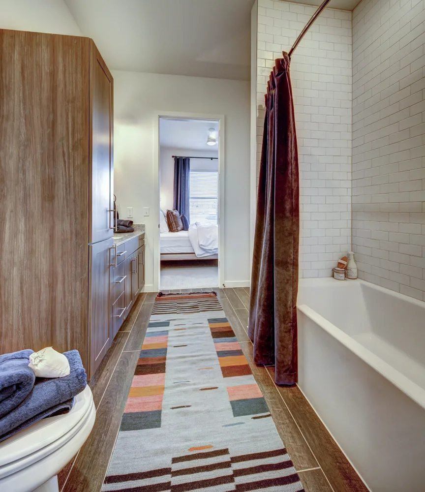 A bathroom with a striped rug on the floor.