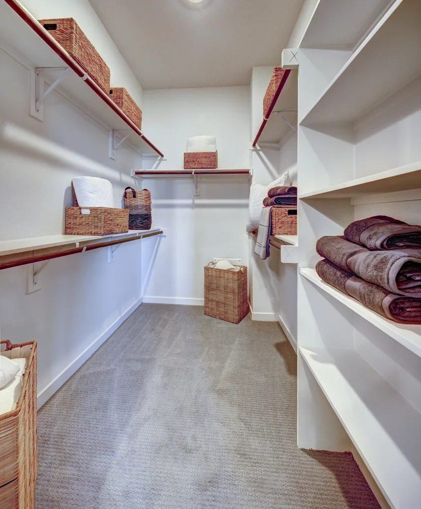 A linen closet with white shelves and baskets.