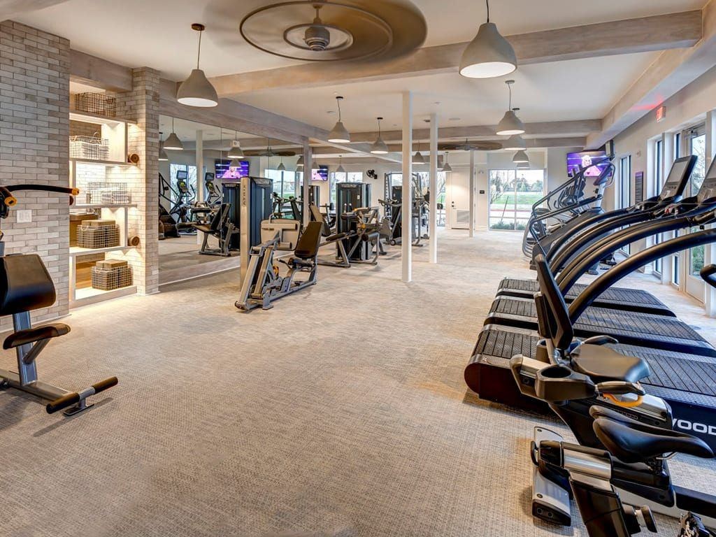 A gym with a variety of equipment including treadmills, weights, and exercise machines.