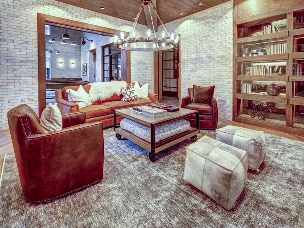 A living room with a brown couch and a white rug.