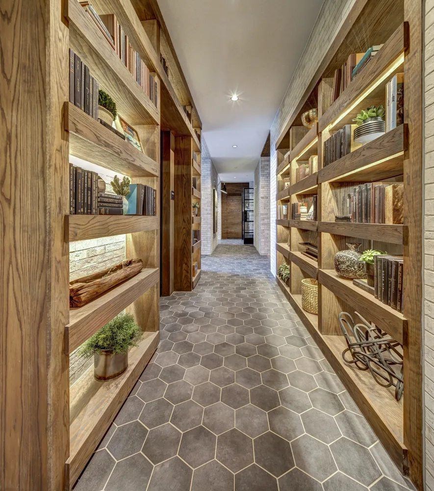 A long hallway with wooden shelves on the side and a grey floor.