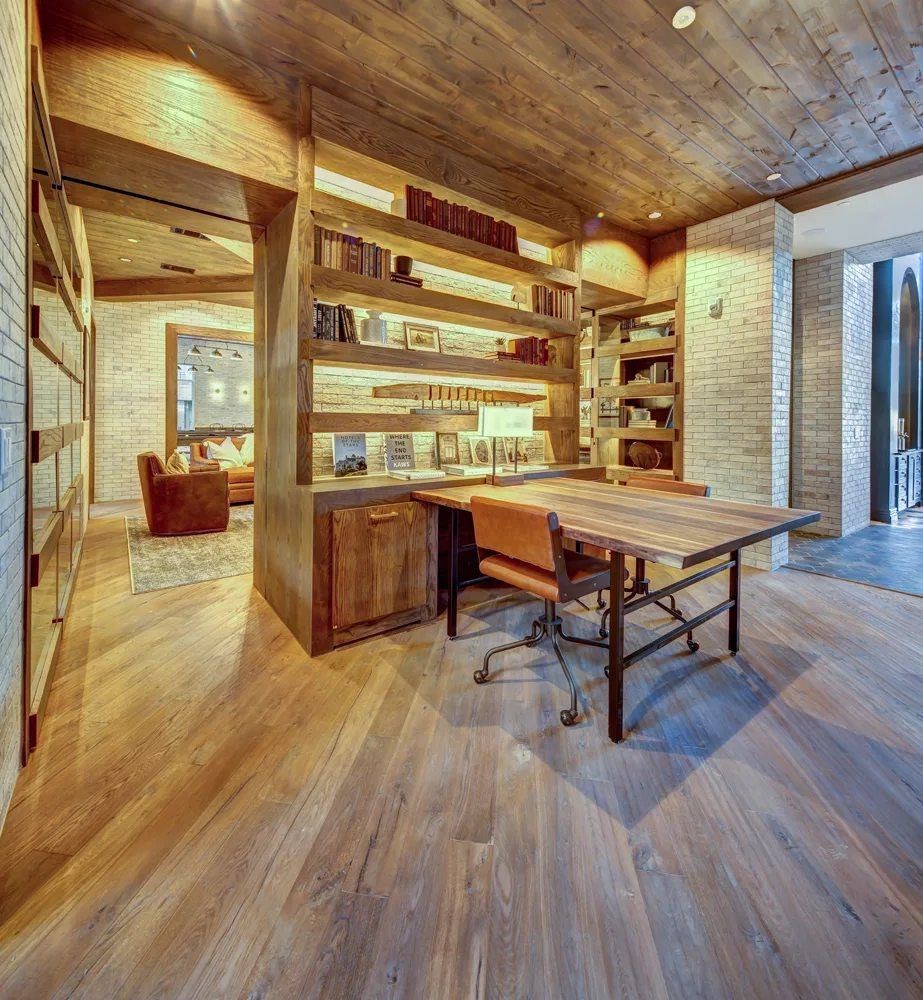 A room with a wooden floor and a long wooden table with chairs.