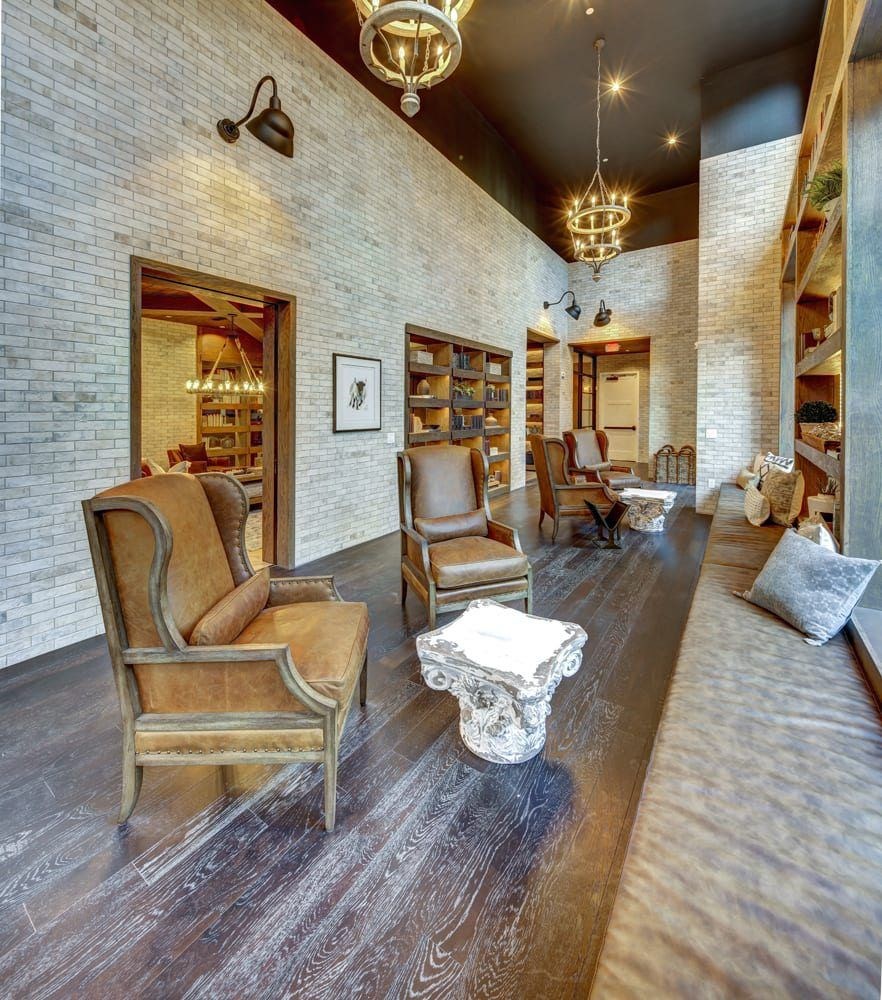 A living room with a long couch and a chair with a white pillow on it.