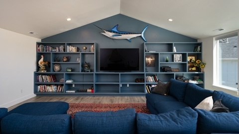 A living room with a blue couch and a television mounted on the wall.