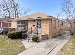 A small house with a brick facade and a black metal fence.