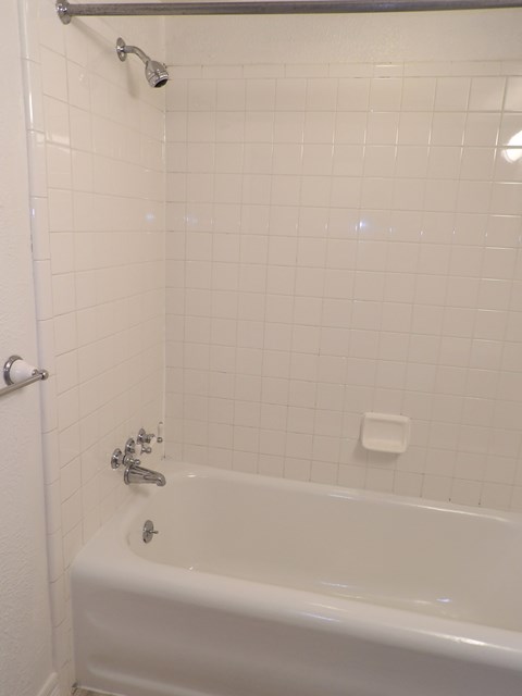 A white bathtub with a shower head and faucet.