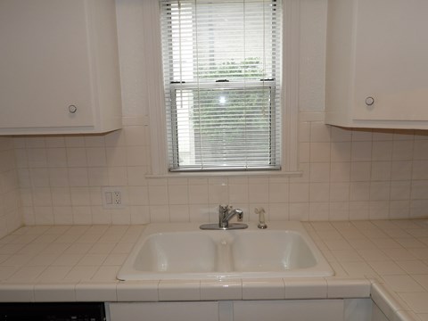 A white sink in a white tiled bathroom.
