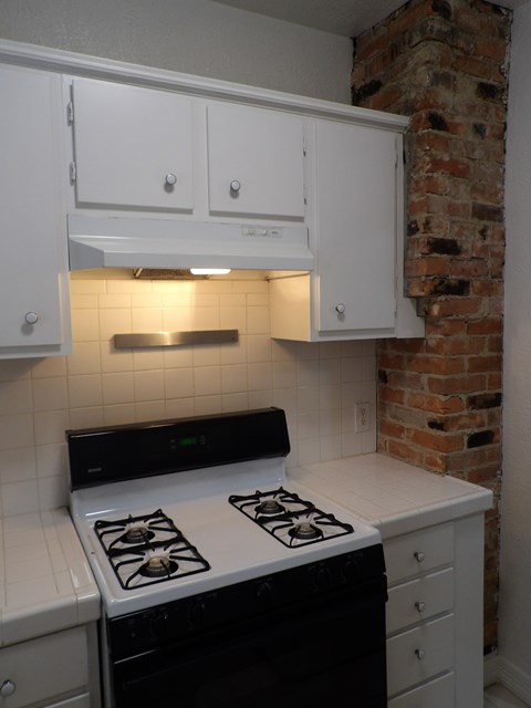 A kitchen with a white stove and white cabinets.