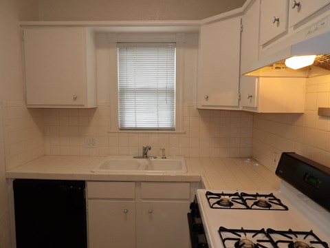 A kitchen with a white stove top oven and a white sink.