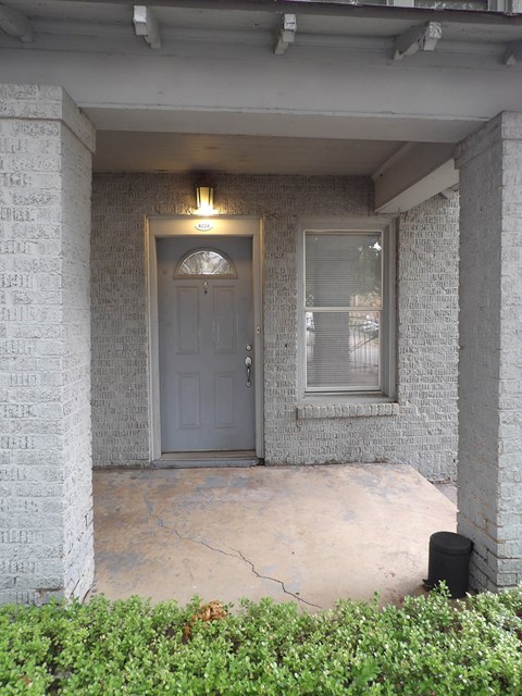A grey door is in a white brick wall.