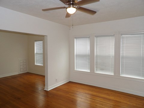 A room with a ceiling fan and wooden floors.