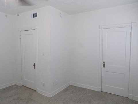 A room with two white doors and a ceiling fan.