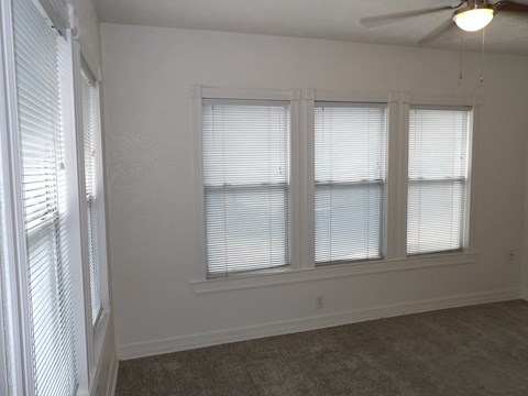 A room with a fan and three windows.