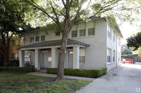 A tree in front of a two-story building.