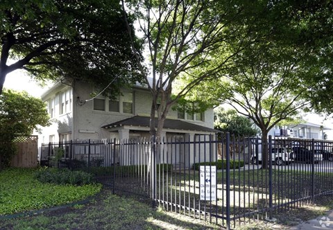 A house with a black fence and a tree in front.