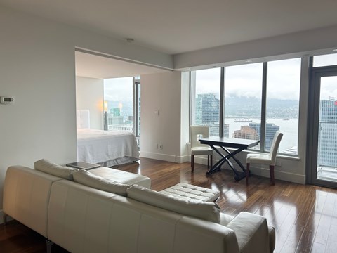 A living room with a couch, chair, and table with a view of the city.