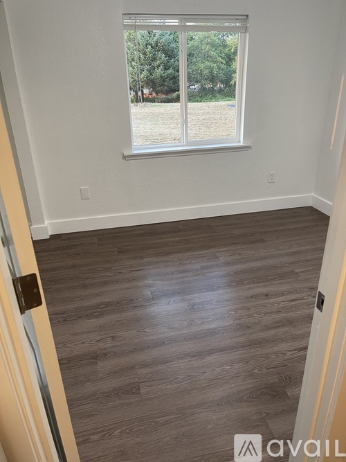 A room with a window and wooden flooring.